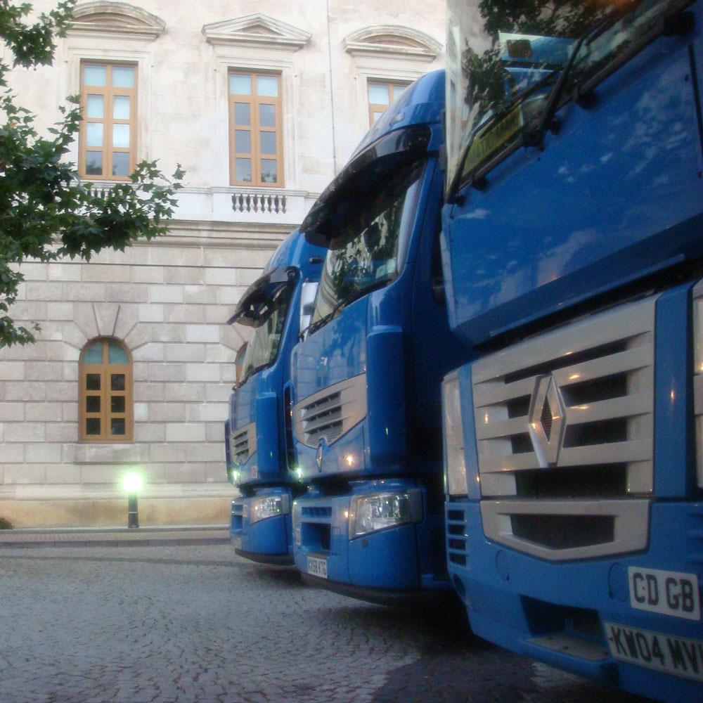 Front of three of our HGV lorries lined up in a cobbled street in front of an embassy.