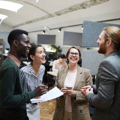 Group of colleagues in an office smiling and laughing in conversation.